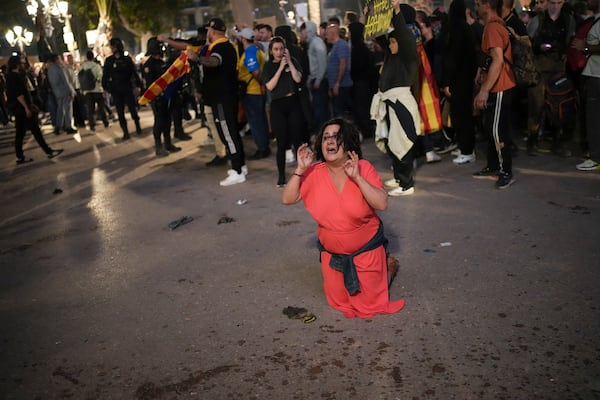 A demonstrator kneels in front of riot police during a protest organized by social and civic groups, denouncing the handling of recent flooding under the slogan "Mazón, Resign," aimed at the president of the regional government Carlos Mazon, in Valencia, Spain, Saturday, Nov. 9, 2024. (AP Photo/Emilio Morenatti)