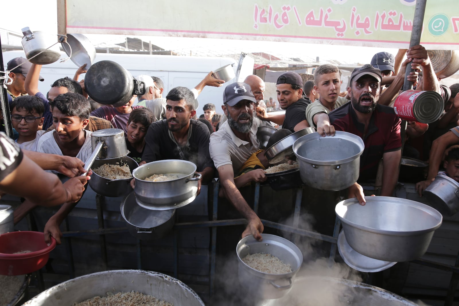 FILE - Palestinian men collect food aid ahead of the upcoming Eid al-Adha holiday in Khan Younis, Gaza Strip, on June 15, 2024. (AP Photo/Jehad Alshrafi, File)