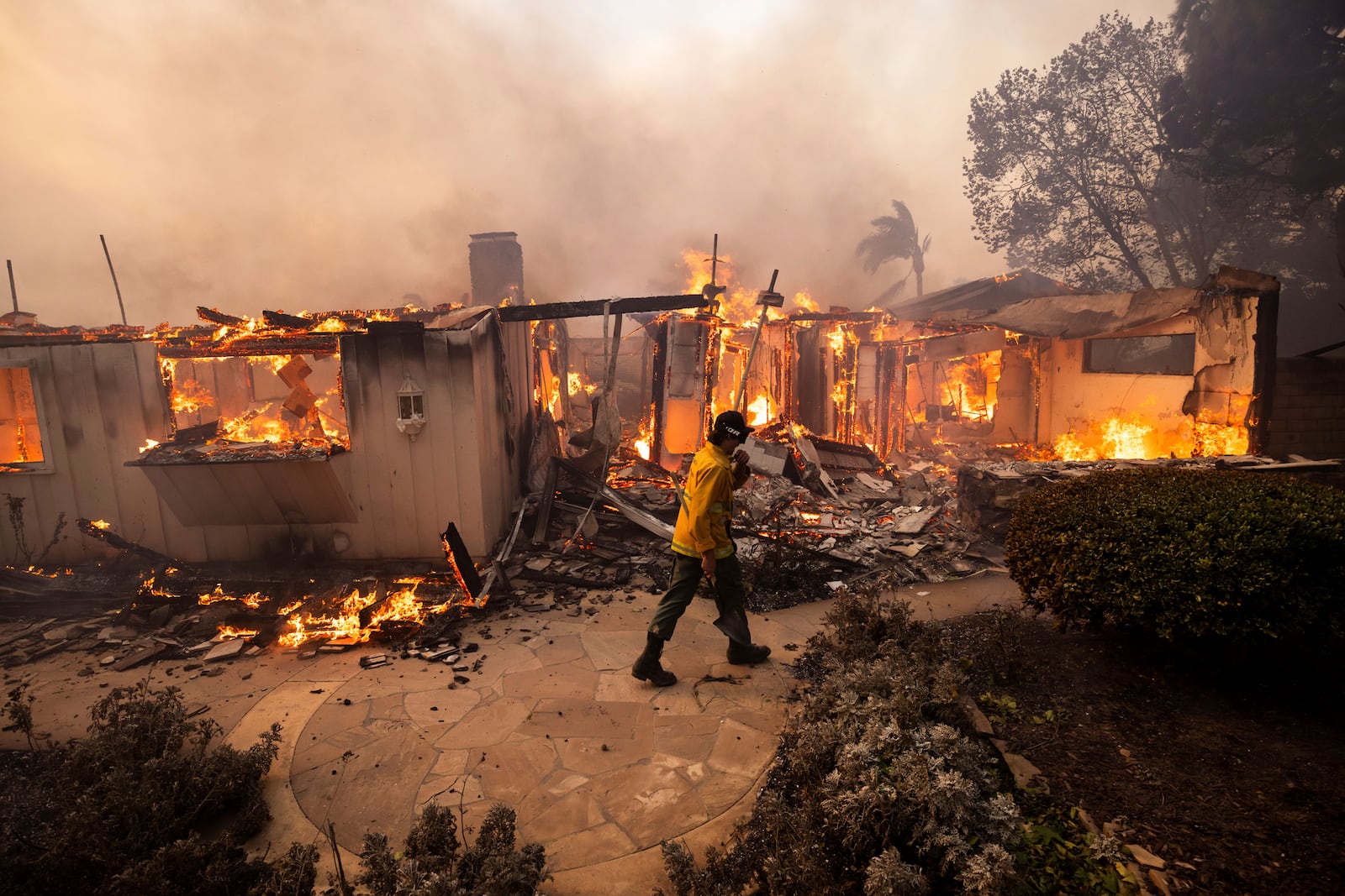 A firefighter passes a burning home in the Mountain fire, Wednesday, Nov. 6, 2024, near Camarillo, Calif. (AP Photo/Ethan Swope)