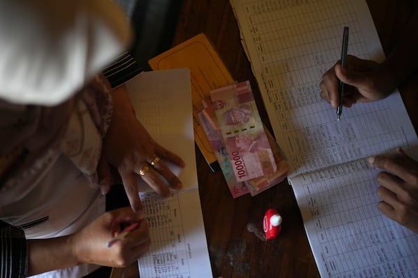 Administrators register member's savings during the gathering of a cocoa farmers' cooperative in Tanjung Rejo, Lampung province, Indonesia, Wednesday, Feb. 19, 2025. (AP Photo/Dita Alangkara)