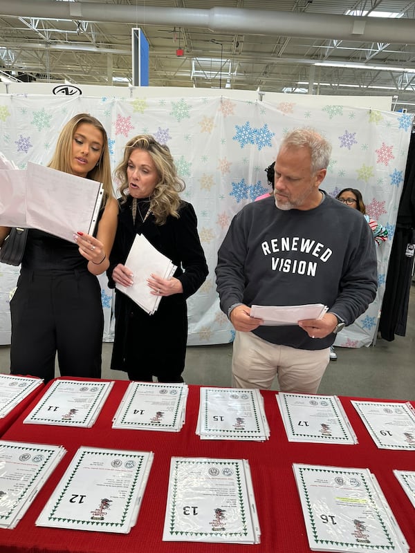 Matt Broms of Alpharetta and his wife Dawn and daughter Allie go over the wish lists of kids (known only by gender and age) to buy gifts for Clark's Christmas Kids program for foster kids at the Roswell Walmart Dec. 8, 2024. RODNEY HO/rho@ajc.com