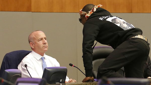 Stevante Clark jumps on the dais in front of a startled Sacramento Mayor Darrell Steinberg, left, during a city council meeting Tuesday, March 27, 2018. Clark, brother of Stephon Clark, disrupted the meeting for several minutes in protest of his brother's March 18 death at the hands of police officers. Stephon Clark, 22, died after two officers fired 20 rounds at him as he stood, unarmed, on the back patio of his grandparents' home.