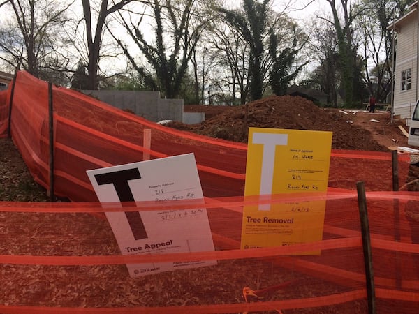 Signs of progress. The yellow sign indicates a planned tree-cutting, while the white sign indicates an appeal of that plan. (Photo by Bill Torpy)