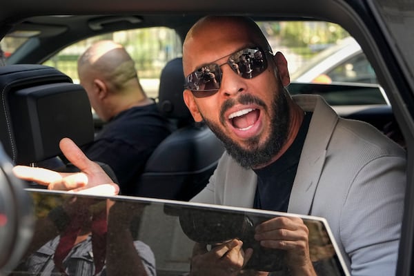 FILE - Andrew Tate sits in a car and talks to reporters surrounding his car after exiting the Court of Appeals building, after a hearing, in Bucharest, Romania, Wednesday, Sept. 4, 2024. (AP Photo/Vadim Ghirda, File)