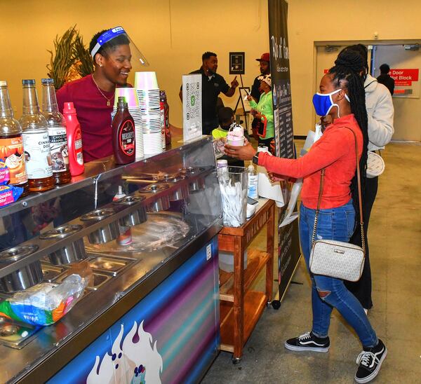 Cecil W. Brown, co-owner of Rolls of Flame rolled ice cream, makes a customer happy at the New Black Wall Street Market in Stonecrest. (Chris Hunt for The Atlanta Journal-Constitution)