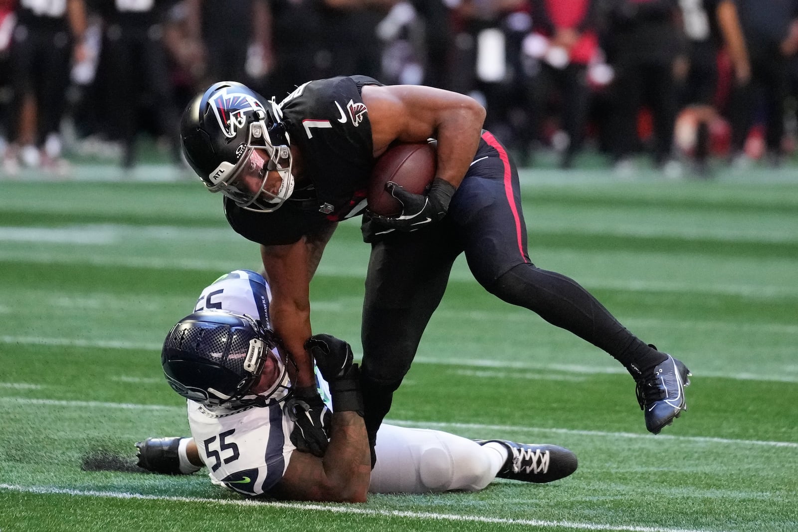 Atlanta Falcons running back Bijan Robinson (7) is tackled by Seattle Seahawks defensive end Dre'Mont Jones (55) during the second half of an NFL football game, Sunday, Oct. 20, 2024, in Atlanta. (AP Photo/ Brynn Anderson)