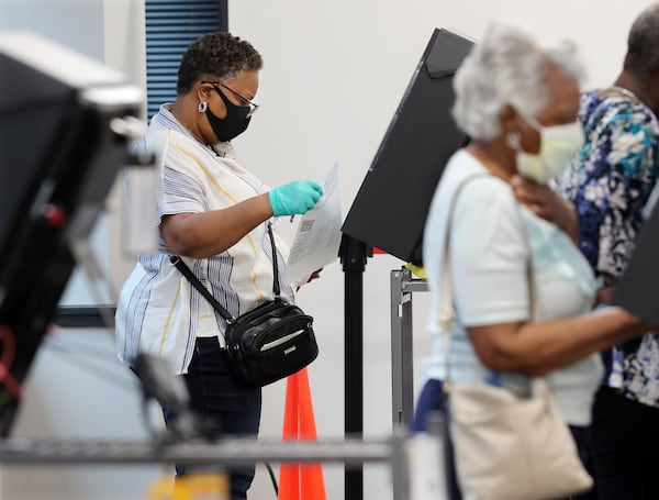 A voter wears a mask and gloves to cast her vote at stations at least six feet apart on the first day of early voting at the Cobb County Board of Elections & Registration on Monday, May 18, 2020, in Marietta. CURTIS COMPTON / CCOMPTON@AJC.COM