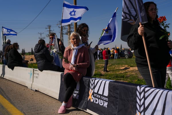 Israelis are waiting on the side of a road where the funeral convoy carrying the coffins of slain hostages Shiri Bibas and her two children, Ariel and Kfir, will pass by near Kibbutz Nir Oz, Israel, Wednesday, Feb. 26, 2025. The mother and her two children were abducted by Hamas on Oct. 7, 2023, and their remains were returned from Gaza to Israel last week as part of a ceasefire agreement with Hamas. (AP Photo/Ohad Zwigenberg)