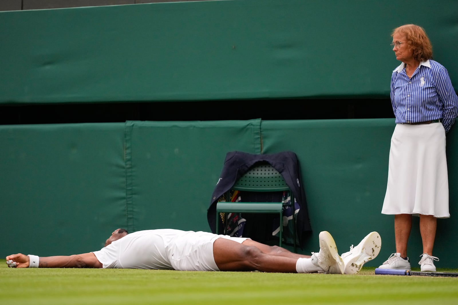 FILE - A line judge looks as Gael Monfils of France lies on the court after during his third round match against Grigor Dimitrov of Bulgaria at the Wimbledon tennis championships in London, on July 5, 2024. That long-held Wimbledon tradition of line judges dressed in elegant uniforms is no more. The All England Club has announced that artificial intelligence will be used to make the 'out' and 'fault' calls at the championships from 2025. (AP Photo/Kirsty Wigglesworth, File)