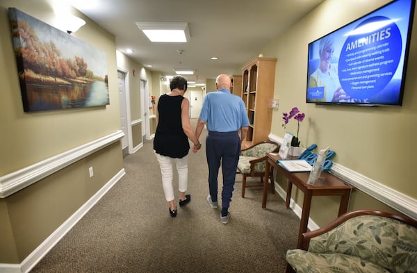 Karen J. Hardwick and her husband, Greg, who has Alzheimer’s disease, hold hands as they return to his room at Addington Place at the Mills in Roswell recently. Greg’s younger brother Scott also battled Alzheimer’s. HYOSUB SHIN / HYOSUB.SHIN@AJC.COM