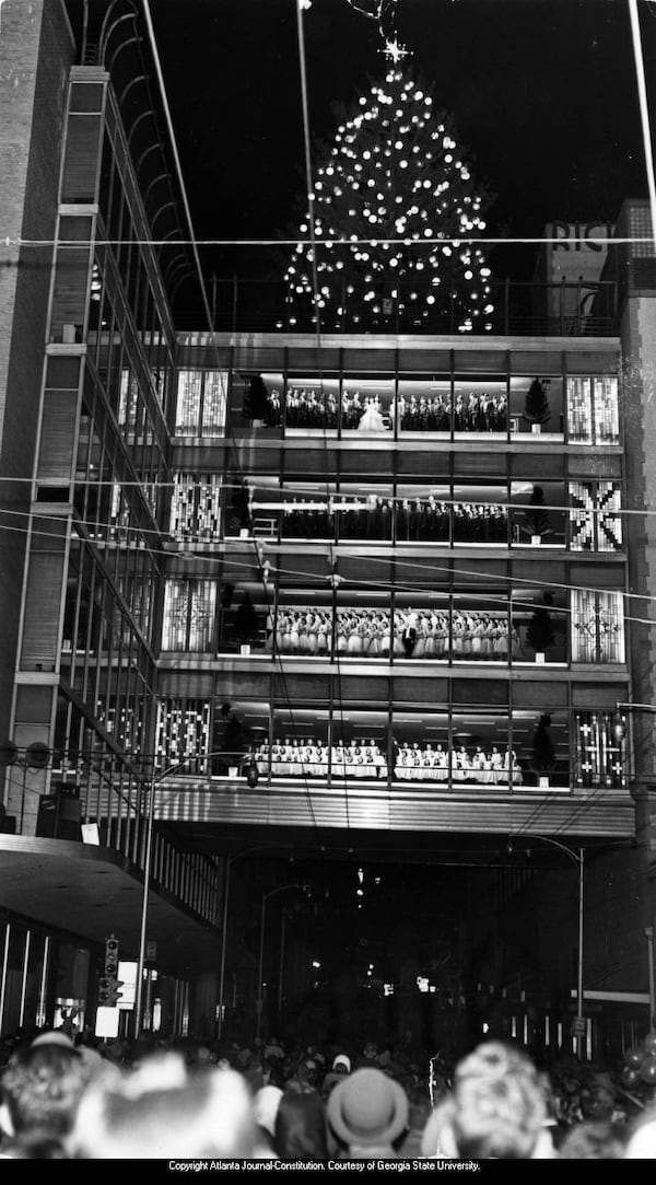 An estimated 100,000 persons jam downtown area as choral group sings of Christmas at the RIch's Great Tree Lighting.  A tenth of city's million see lighting of great tree."  Newspaper caption is date-stamped Nov. 27, 1959.