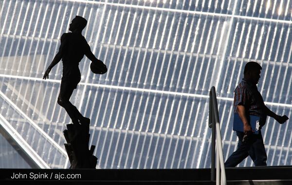 M.D. Khair walks past a statue of Dominique Wilkins in front of Philips Arena on his way to work Tuesday. JOHN SPINK / JSPINK@AJC.COM