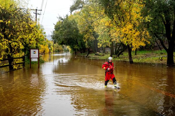 Firefighter Eugene Stipanov walks through floodwaters while responding to a rescue call in unincorporated Sonoma County, Calif., on Friday, Nov. 22, 2024. (AP Photo/Noah Berger)