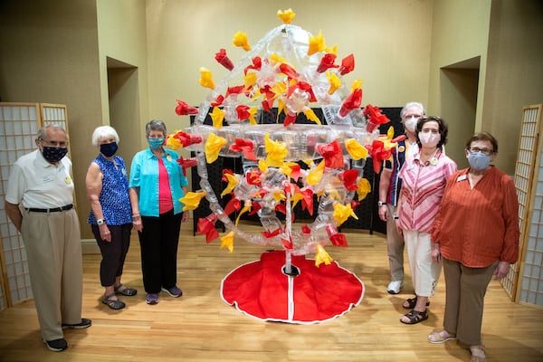 Canterbury Court residents Fritz Toussaint (from left), Martha Solano, LuAnne Schwarz, Vince Capka, Mary Capka and Karen Evan stand near their 6-foot diameter pop art rendering of the novel coronavirus on display in the Canterbury community center. PHIL SKINNER FOR THE ATLANTA JOURNAL-CONSTITUTION.