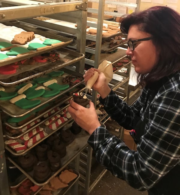 Taj Ma-Hound owner Krista Aversano taught herself the art of working with icing. Here, she’s putting a Santa hat on a Happy Poo Emoji, the shop’s most popular treat. CONTRIBUTED BY KRISTA AVERSANO/TAJ MA-HOUND