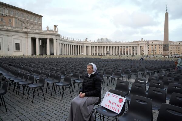 Sister Veronika Mroz, of Poland, sits beside a placard with a picture of Pope Francis, reading: "Best wishes His Holiness" as she waits in St. Peter's Square at the Vatican for the start of a vigil rosary for the recovery of Pope Francis who is being treated for pneumonia at Rome's Agostino Gemelli Polyclinic, Thursday, March 13, 2025. (AP Photo/Gregorio Borgia)