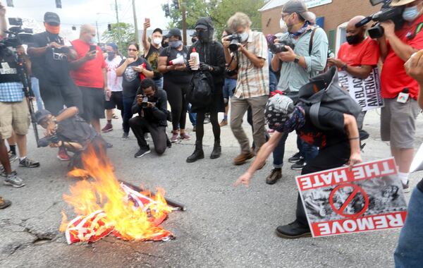 8/15/20 - Stone Mountain, GA - Counter protestors set a Confederate flag on fire, then added an American flag to the fire, as protestors and counter protestors face off in the town of Stone Mountain after Stone Mountain Park was closed.  Several far-right groups, including militias and white supremacists, were planning to rally Saturday at Stone Mountain, and a broad coalition of leftist anti-racist groups are organizing a counter-demonstration. Local authorities, who have been closely monitoring online chatter about the rally, are bracing for possible conflict.   Jenni Girtman for the Atlanta Journal Constitution