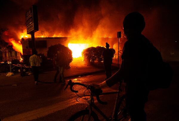 A protester looks  at a burning building early Saturday in Minneapolis. 