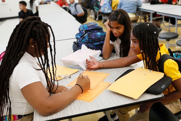 August 1, 2019, 2019 - McDonough - Sixth graders Jassiah Allen (from left) Hannah Estacio and Victoria Phillip fill out their class preferences as they wait in the cafeteria for the school day to begin.  Henry County students have their first day of school at the brand new McDonough Middle School. Thursday was the first day of school of the 2019-2020 school year.  Bob Andres / robert.andres@ajc.com