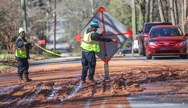 Crews work to direct traffic and fix a broken water main on McClendon Drive in DeKalb County on Friday, Feb. 2, 2024. (John Spink/jspink@ajc.com)