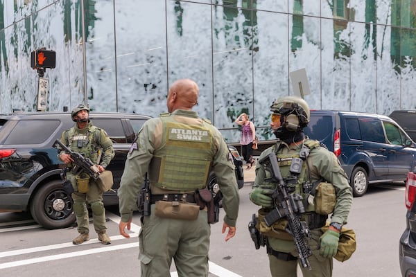 A SWAT team gathers outside a condominium building on 16th and Spring Street in Midtown Atlanta on Monday, August 22, 2022. A woman was arrested at the Atlanta airport a little more than two hours after shots were fired at the building, according to Atlanta police.The woman is suspected of shooting three people. (Arvin Temkar / arvin.temkar@ajc.com)