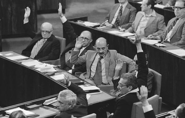 FILE - Israel Minister, counter clockwise from foreground, Ariel Sharon, Agriculture, Ezer Weizman, Defense, Moshe Dayan, Foreign, Yigal Yadin, Deputy Premier, Menachem Begin, Premier, and Simha Erlich, Finance, raise their hands during a vote, ending the parliament session on the U.S. peace proposals for an agreement between Egypt and Israel in Jerusalem on March 22, 1979. (AP Photo/Max Nash, File)