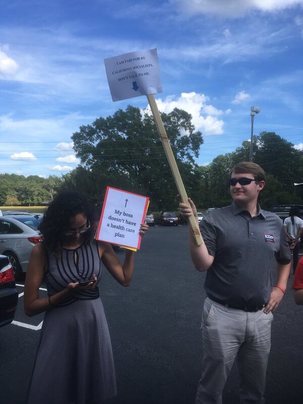 Dueling operatives at a Brian Kemp campaign rally in Newnan. Jennifer Brett/AJC