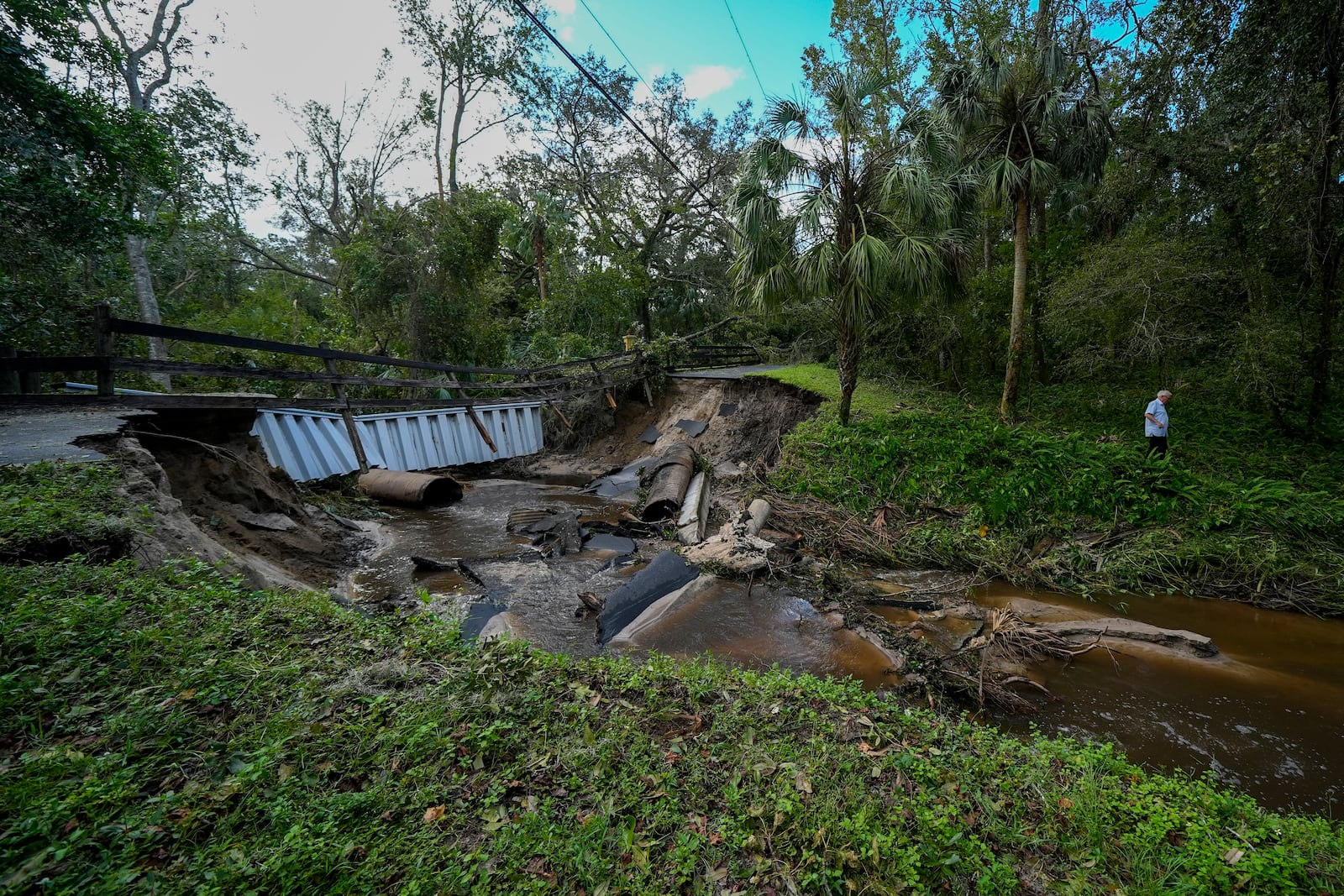 Del Ockey, a seasonal Florida resident from Canada, walks near the damaged bridge to his property from Hurricane Milton, Friday, Oct. 11, 2024, in Riverview, Fla. (AP Photo/Julio Cortez)