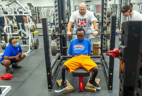 Dave Githutu, a Milton High School weight-lifter who regularly competes in the special olympics, trains at Roswell Barbell with his coach Josh Porter on Tuesday, Aug 23, 2022 and team members.  The athlete is competing in England in September at an able-bodied competition before a scheduled heart surgery scheduled for Spring.  (Jenni Girtman for The Atlanta Journal-Constitution)