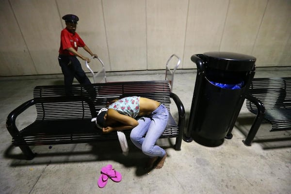 After most flights have concluded for the night a woman sleeps on the bench outside the south baggage claim at Hartsfield-Jackson Atlanta International Airport on Tuesday, Oct. 1, 2013, in Atlanta.