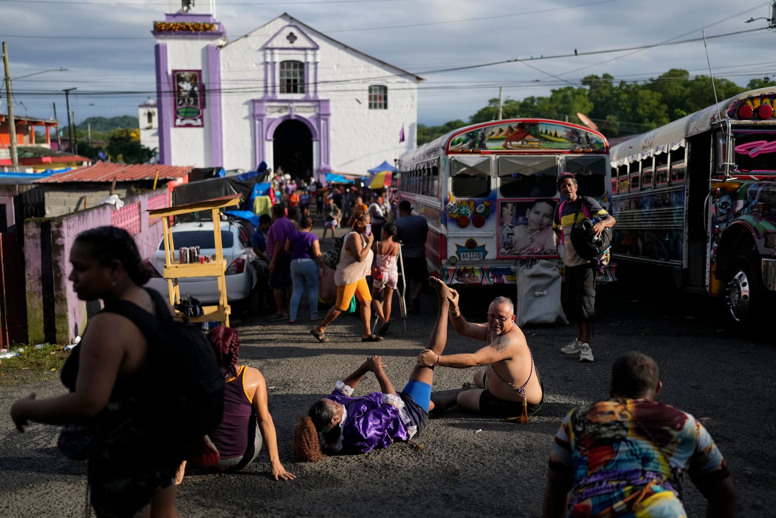 Pilgrim Ernesto Troya stretches his friend's leg as they take a break from crawling on their knees to San Felipe Church to honor the Black Christ in Portobelo, Panama, Monday, Oct. 21, 2024, during a festival celebrating the iconic statue that was found on the shore in 1658. (AP Photo/Matias Delacroix)