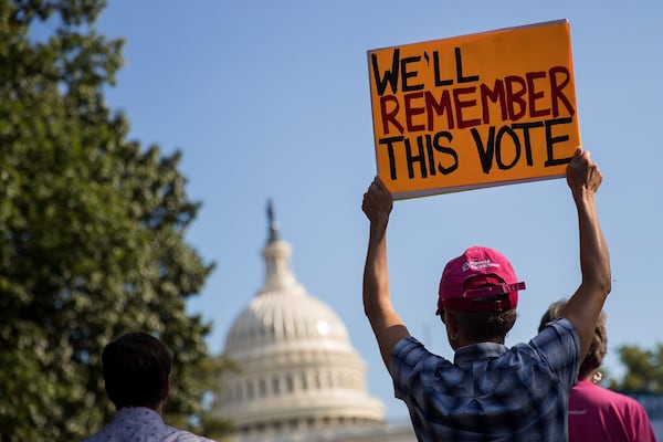 A protester holds up a sign on July 26, 2017, on Capitol Hill in Washington, during a rally against the Republican plan to repeal and replace the Affordable Care Act, also known as Obamacare. (Photo by Drew Angerer/Getty Images)