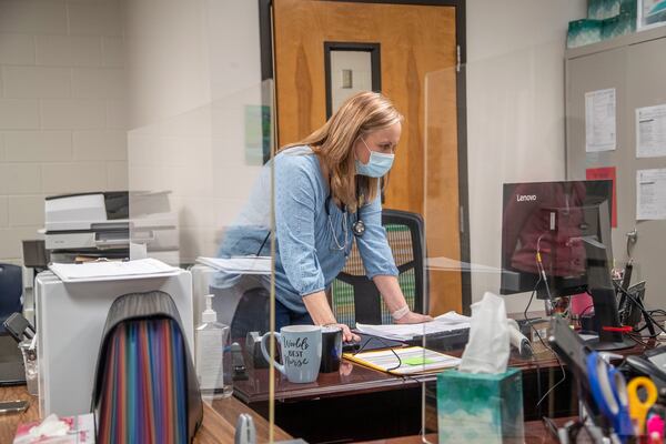 In this file photo, Mill Creek High School nurse Kathy Catapano reads through emails at her desk in the school’s clinic in Hoschton. (Alyssa Pointer / Alyssa.Pointer@ajc.com)