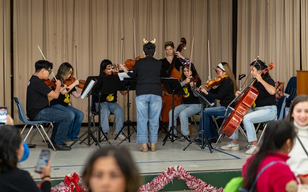 Some musicians from the Buford Highway Orchestra Project, which teaches orchestral music to over 50 students, play holiday music as attendees collect clothes and receive COVID vaccines. Saturday, December 14, 2024 (Ben Hendren for the Atlanta Journal-Constitution)