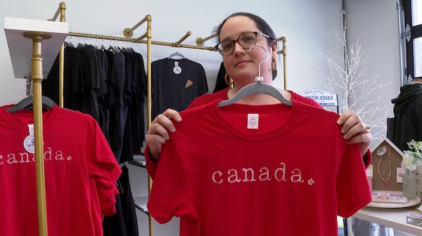 In this image made from video, Whiskeyjack Boutique owner Katie Stokes holds up a shirt for sale at her gift shop Tuesday, March 4, 2025, in Windsor, Ontario. (AP Photo/Mike Householder)