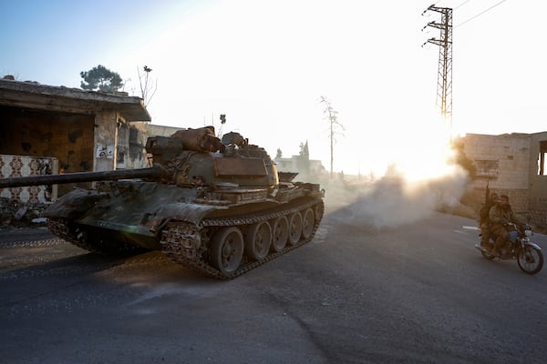 Syrian opposition fighters drive a motorcycle and an armoured vehicle seized from the Syrian army in the town of Maarat al-Numan, south of Idlib, Syria, Tuesday Dec. 3, 2024.(AP Photo/Omar Albam)