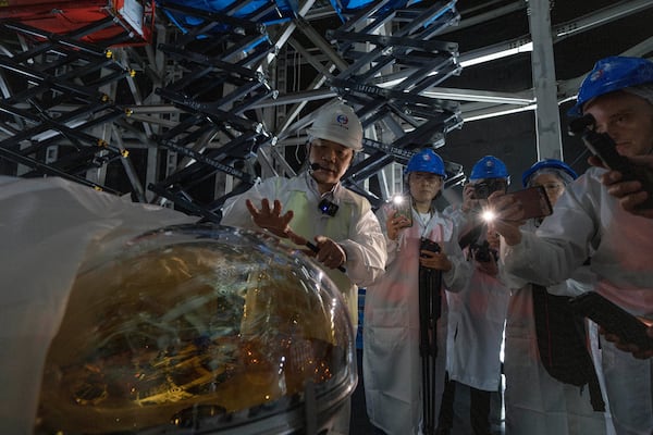 Wang Yifang, chief scientist and project manager at the Jiangmen Underground Neutrino Observatory briefs visitors on a Photomultiplier Tube used to convert photons into electrical signal, of which 20,000 pieces are used in the cosmic detector located 2297 feet (700 meters) underground in Kaiping, southern China's Guangdong province on Friday, Oct. 11, 2024. (AP Photo/Ng Han Guan)