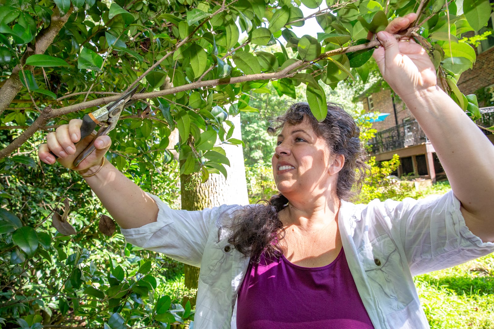 Tamara Nicolai, who dealt with long-covid health problems for months after contracting Covid-19 in 2020, trims back a branch hanging over the path in her yard in Avondale Estates on Friday, Sept 16, 2022.  The experience with the virus changed her lifestyle and perspective; she is no longer a touring musician as she was for years before the pandemic.  (Jenni Girtman for The Atlanta Journal-Constitution)