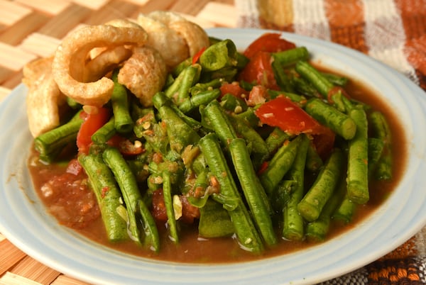 This Thum Mak Tua (Long Bean Salad) is garnished with fried pork rinds, a traditional accompaniment for any thum salad. (Styling by Ilene Rouamvongsor / Chris Hunt for the AJC)