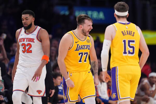 Los Angeles Lakers guard Luka Doncic, center, celebrates after scoring as New York Knicks center Karl-Anthony Towns, left, walks away and guard Austin Reaves stands by during the second half of an NBA basketball game Thursday, March 6, 2025, in Los Angeles. (AP Photo/Mark J. Terrill)