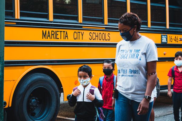 Lockheed Elementary School students are escorted from the bus Tuesday by a staff member.