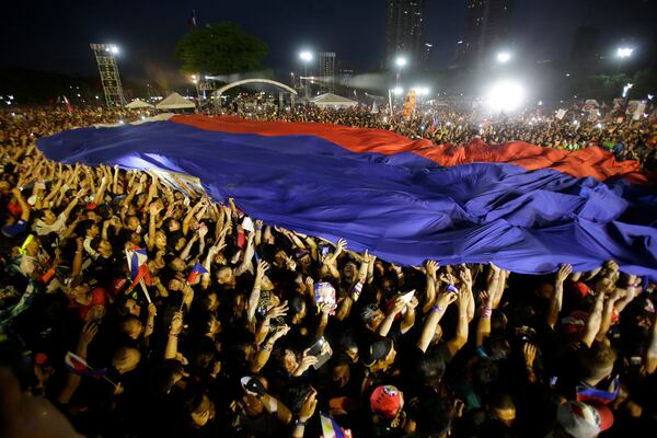 FILE- Supporters pass around the Philippine flag during the final campaign rally of Philippine presidential race front-runner Davao city mayor Rodrigo Duterte in Manila, Philippines on Saturday, May 7, 2016. (AP Photo/Aaron Favila, File)