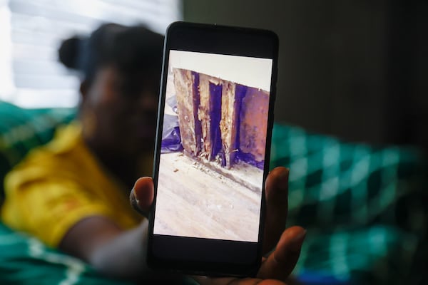 Nora Williams holds up her cellphone to show a photo of mold and damage in her former apartment. (Natrice Miller/natrice.miller@ajc.com)  