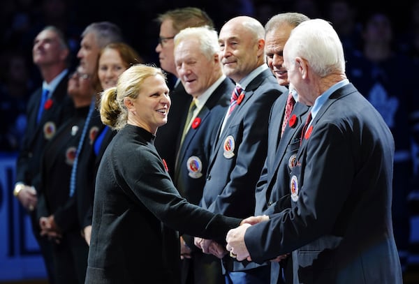 2024 Hockey Hall of Fame inductee Natalie Darwitz, left, shakes hands with Lanny McDonald, right, during a ceremony prior to NHL hockey game action between the Detroit Red Wings and the Toronto Maple Leafs in Toronto, Friday, Nov. 8, 2024. (Frank Gunn/The Canadian Press via AP)