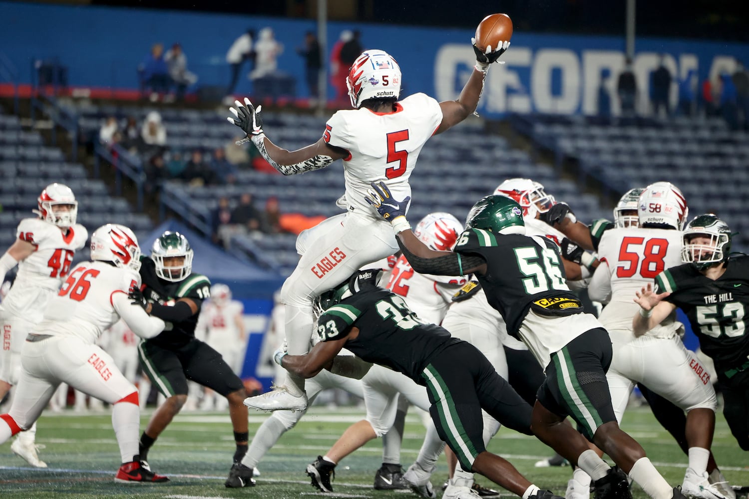 December 11, 2021 - Atlanta, Ga: Milton running back Jordan McDonald (5) attempts a pass as he is hit by Collins Hill linebacker Rich Dorsey (33) and defensive lineman Jaylen George (56) during the second half of the Class 7A state title football game at Georgia State Center Parc Stadium Saturday, December 11, 2021, Atlanta. Collins Hill won 24-8. JASON GETZ FOR THE ATLANTA JOURNAL-CONSTITUTION