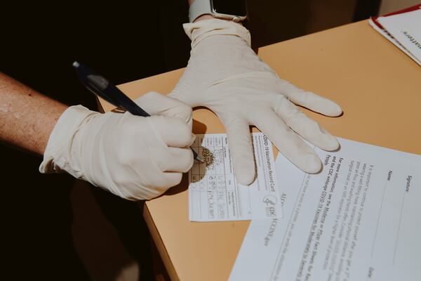 This file photo shows a health care worker filling out a coronavirus vaccination card in Jackson, Ala. (Charity Rachelle/The New York Times)