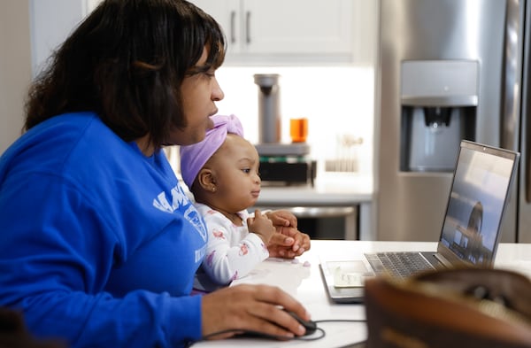 Precious Andrews works from home while caring for her nine month old daughter Ryleigh on Friday, February 10, 2023. (Natrice Miller/ Natrice.miller@ajc.com)