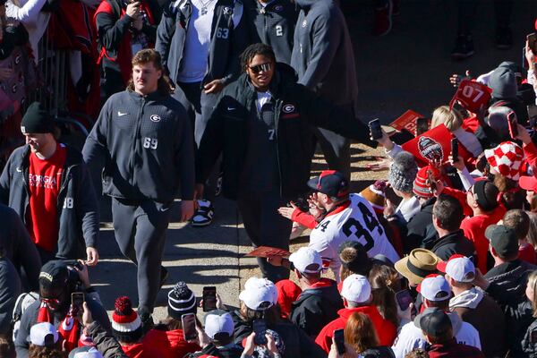 Georgia offensive lineman Devin Willock (77, center wearing glasses) walks with fellow offensive lineman Tate Ratledge (69, left) and others during the Dawg Walk in the 2022 National Championship Celebration on Saturday at Sanford Stadium. (Jason Getz / Jason.Getz@ajc.com)