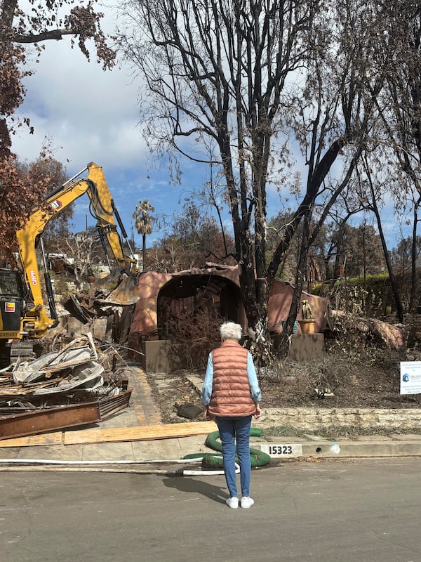 This image provided by Carolyn Kiefer shows her mother Katherine Kiefer, 82, looking at her burned home destroyed by the Palisades Fire where her cat Aggie went missing on Wednesday, Jan. 8, 2025, in Los Angeles. (Carolyn Kiefer via AP)