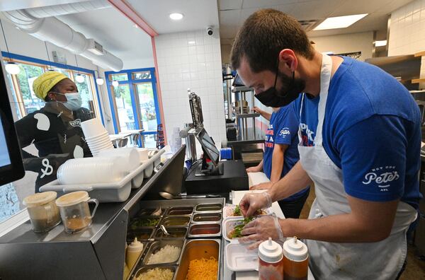  Alii Mathews (right), operating partner, prepares hotdogs as customer Anana Harris (left) waits at Hot Dog Pete's near the Center Parc Stadium in Atlanta on Tuesday. Businesses like Pete's expect to get a boost from football crowds this season. (Hyosub Shin / Hyosub.Shin@ajc.com)